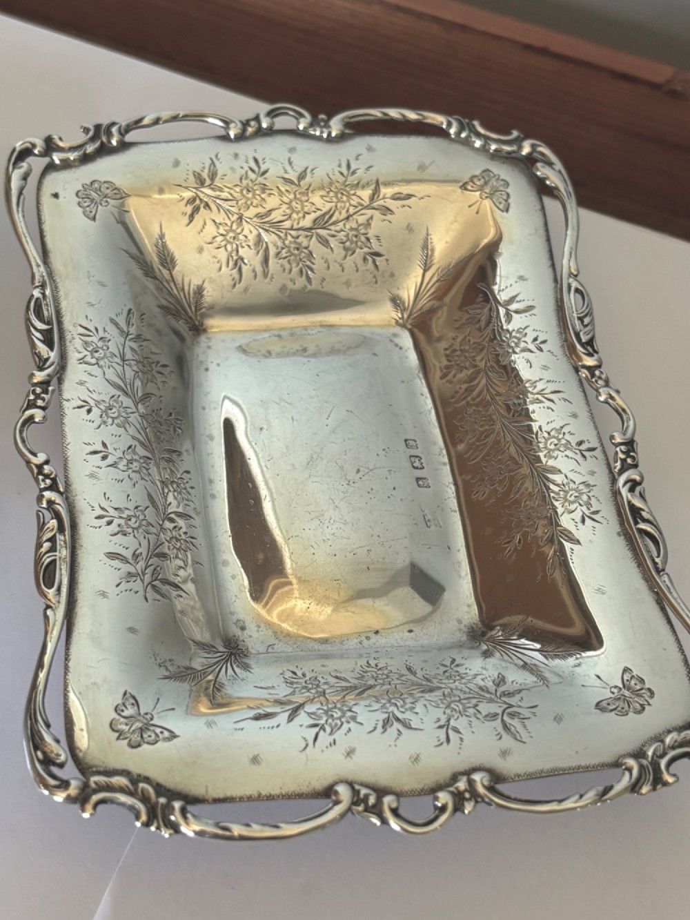 A pair of rectangular Edwardian sterling silver trinket dishes featuring pierced scrollwork borders and engraved floral decoration. View IX