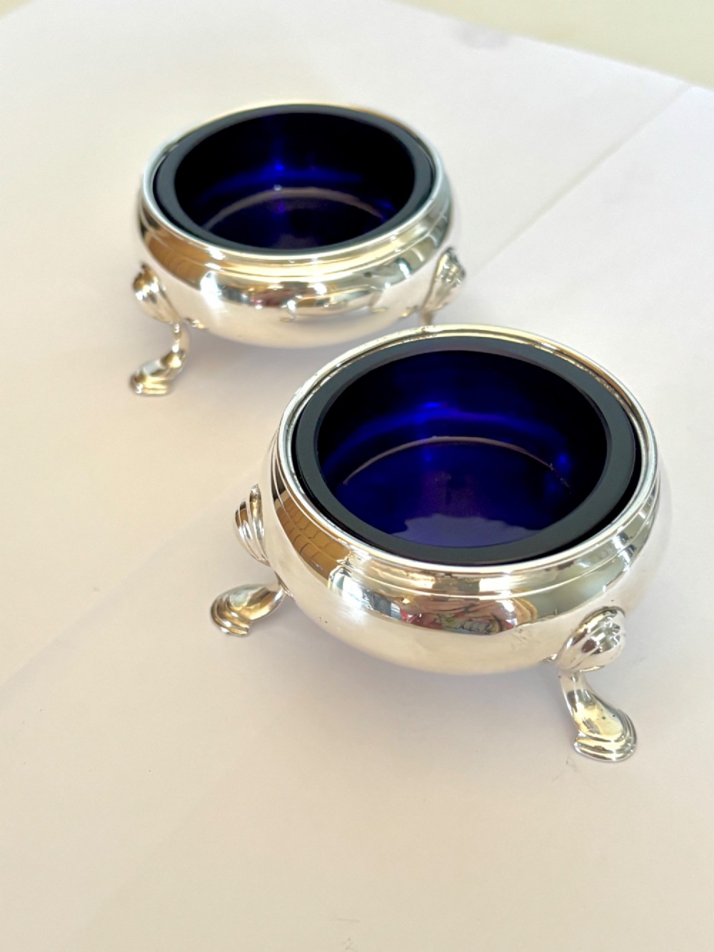 A pair of round 18th-century sterling silver open salt cellars with cobalt blue glass liners, raised on three hoof feet. View III