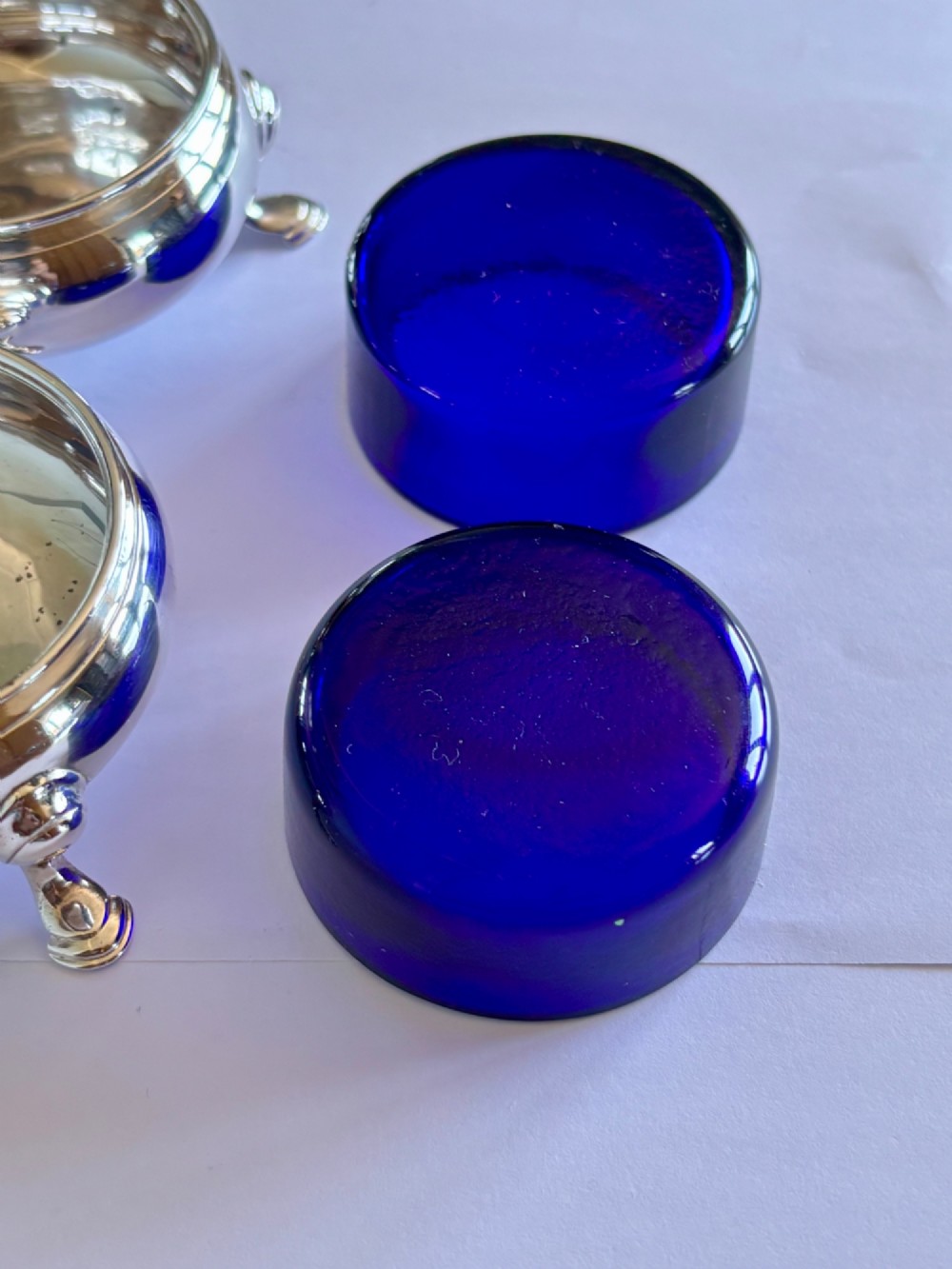 A pair of round 18th-century sterling silver open salt cellars with cobalt blue glass liners, raised on three hoof feet. View VII