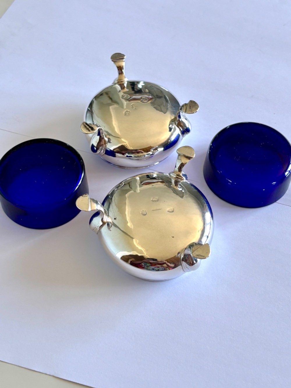A pair of round 18th-century sterling silver open salt cellars with cobalt blue glass liners, raised on three hoof feet. View XV