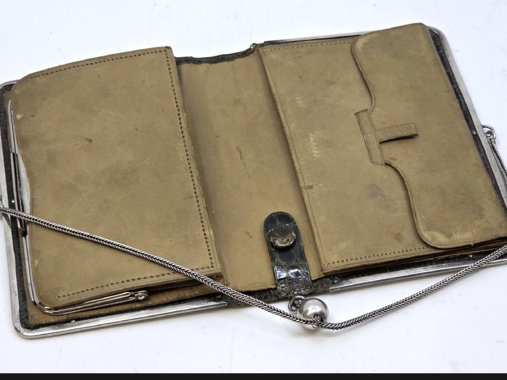 An Art Nouveau dark brown crocodile skin purse featuring hallmarked sterling silver whiplash corner mounts, a central silver cartouche with bow detailing, and a silver chain strap. View VI