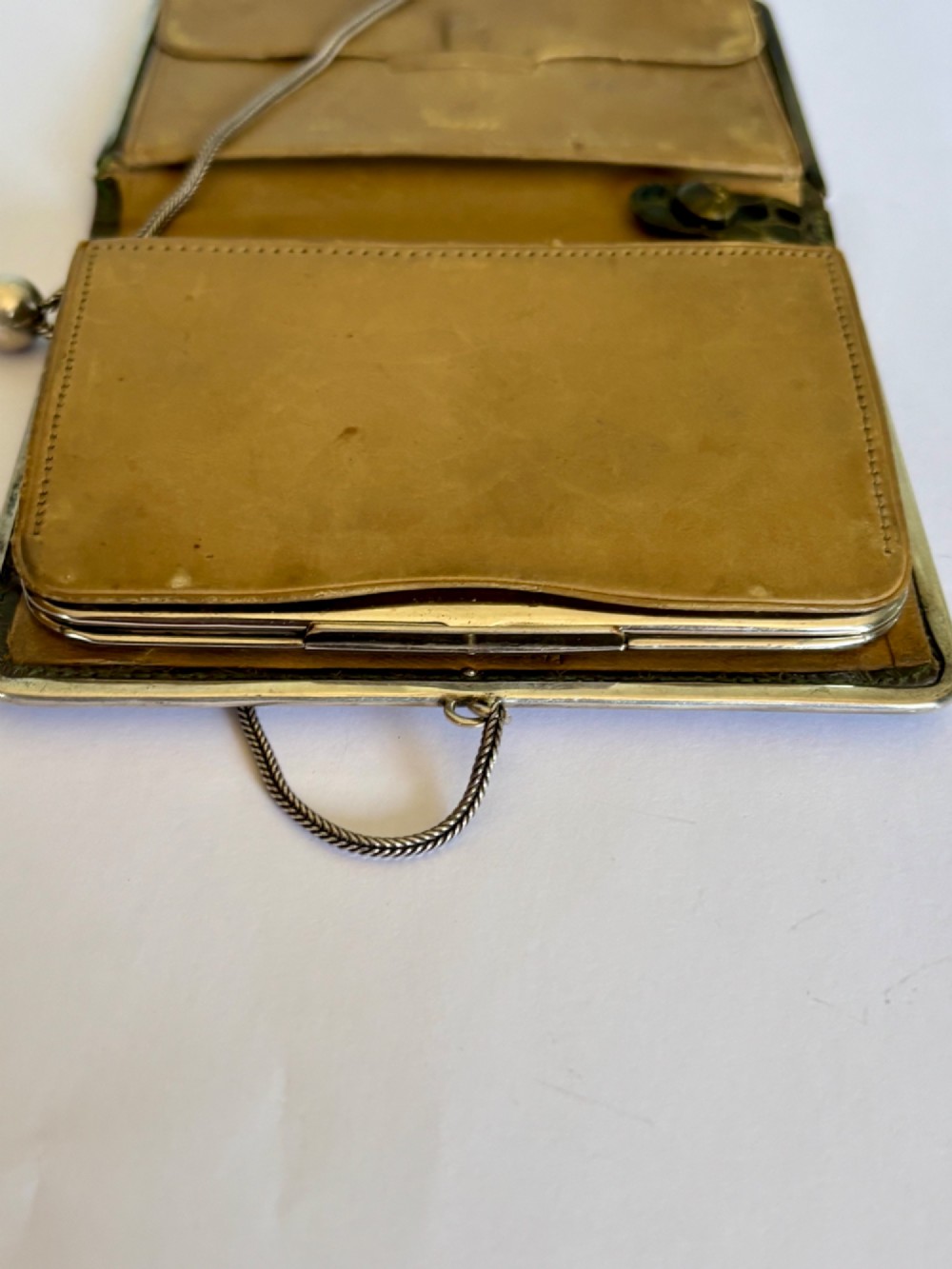 An Art Nouveau dark brown crocodile skin purse featuring hallmarked sterling silver whiplash corner mounts, a central silver cartouche with bow detailing, and a silver chain strap. View XII
