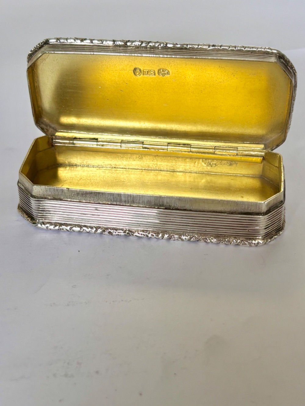 An open rectangular William IV silver gilt snuff box featuring reeded side panels, chased borders, and clear silver hallmarks inside the gilded lid. View II