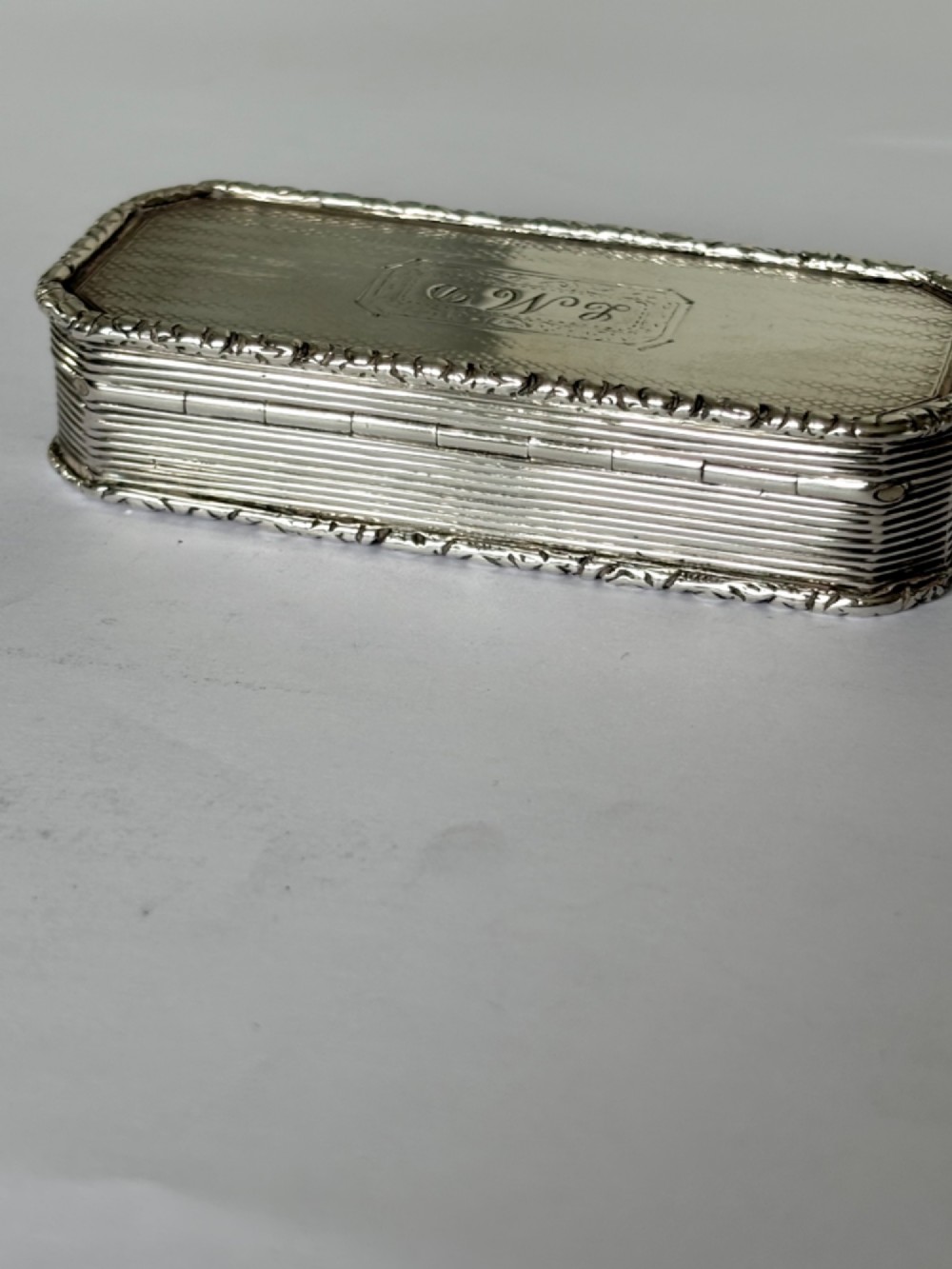 An open rectangular William IV silver gilt snuff box featuring reeded side panels, chased borders, and clear silver hallmarks inside the gilded lid. View VIII