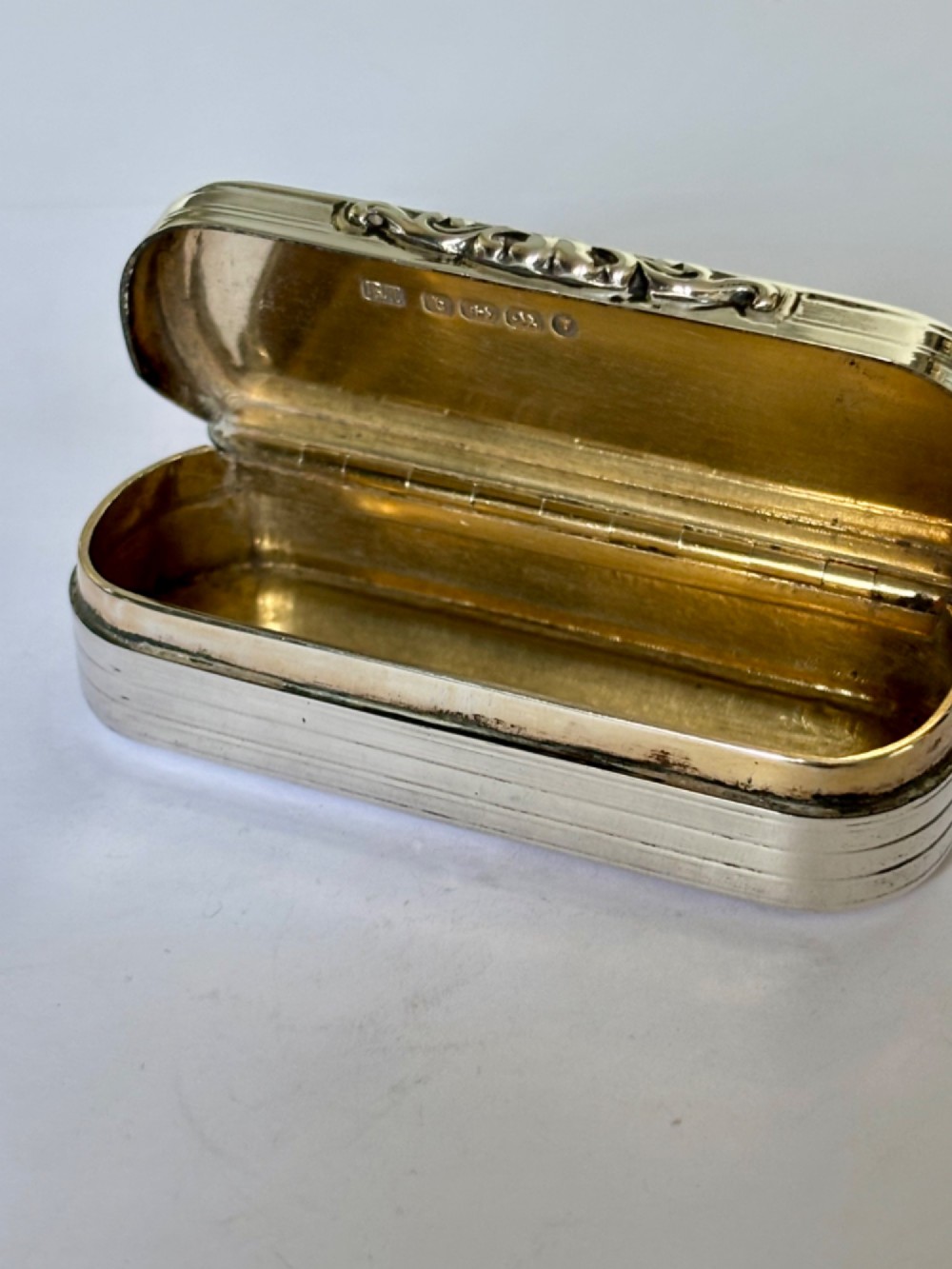 A Victorian silver gilt rectangular snuff box featuring engine-turned reeded decoration and a central rectangular cartouche on the lid. View IX
