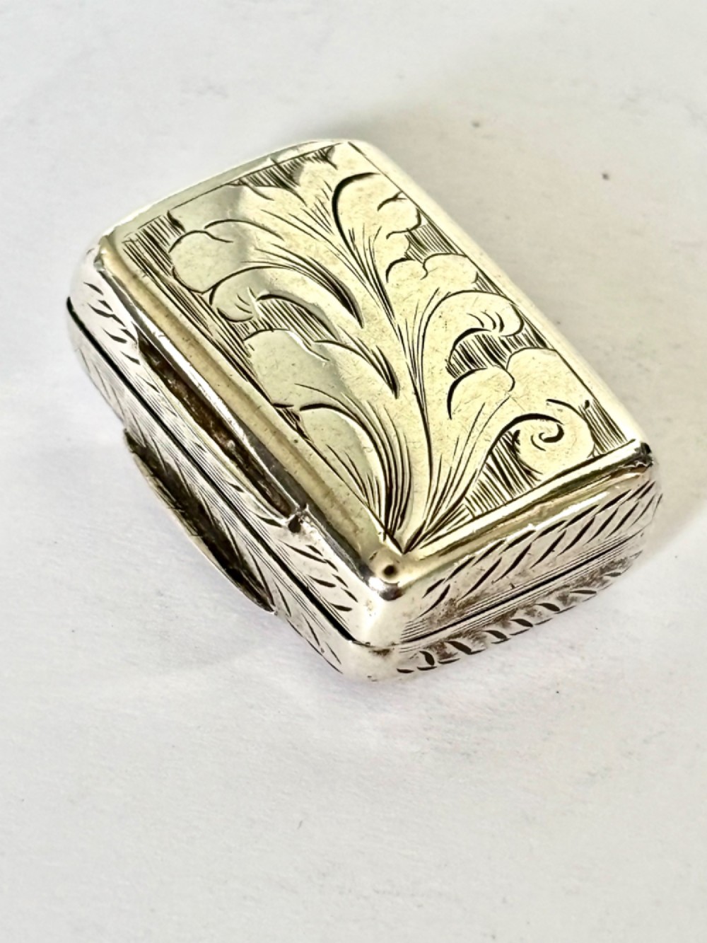 An early Victorian rectangular sterling silver vinaigrette featuring intricate foliate scroll engraving and a central unengraved cartouche. View II