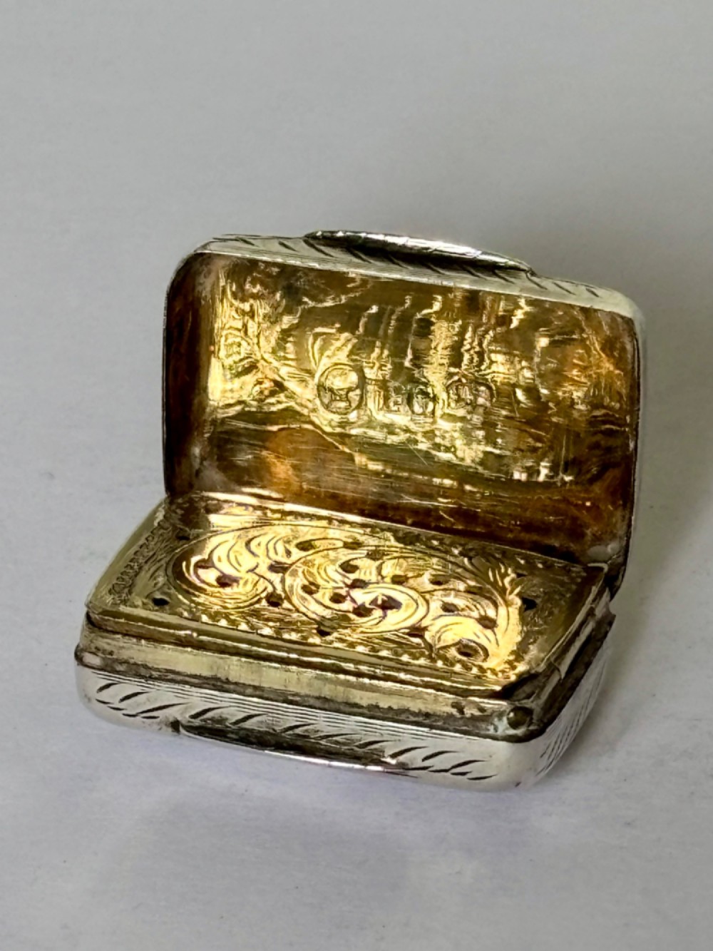 An early Victorian rectangular sterling silver vinaigrette featuring intricate foliate scroll engraving and a central unengraved cartouche. View III