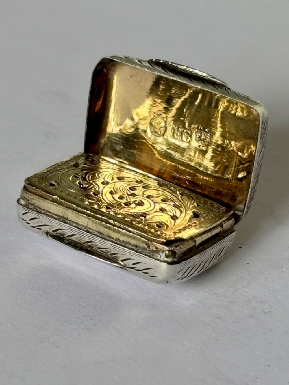 An early Victorian rectangular sterling silver vinaigrette featuring intricate foliate scroll engraving and a central unengraved cartouche. View IV