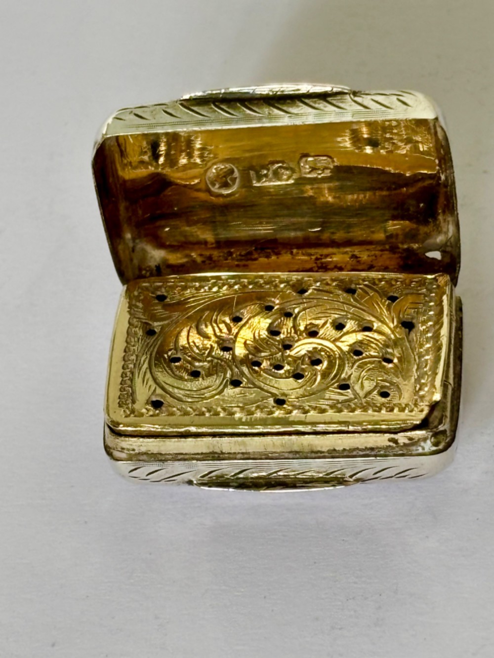 An early Victorian rectangular sterling silver vinaigrette featuring intricate foliate scroll engraving and a central unengraved cartouche. View V