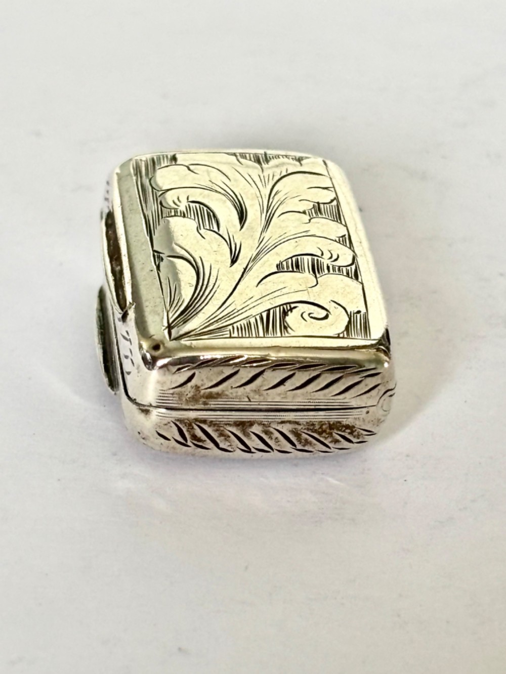 An early Victorian rectangular sterling silver vinaigrette featuring intricate foliate scroll engraving and a central unengraved cartouche. View VI