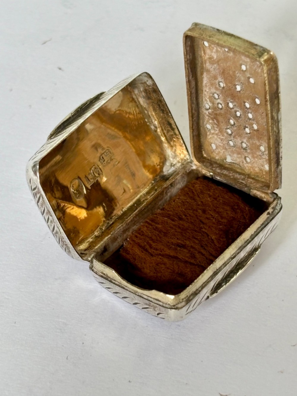 An early Victorian rectangular sterling silver vinaigrette featuring intricate foliate scroll engraving and a central unengraved cartouche. View IX