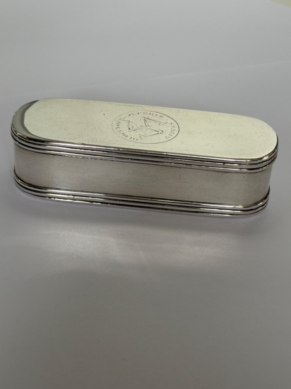 An elongated Georgian sterling silver snuff box with rounded ends, engraved on the lid with the Isle of Man triskelion crest.