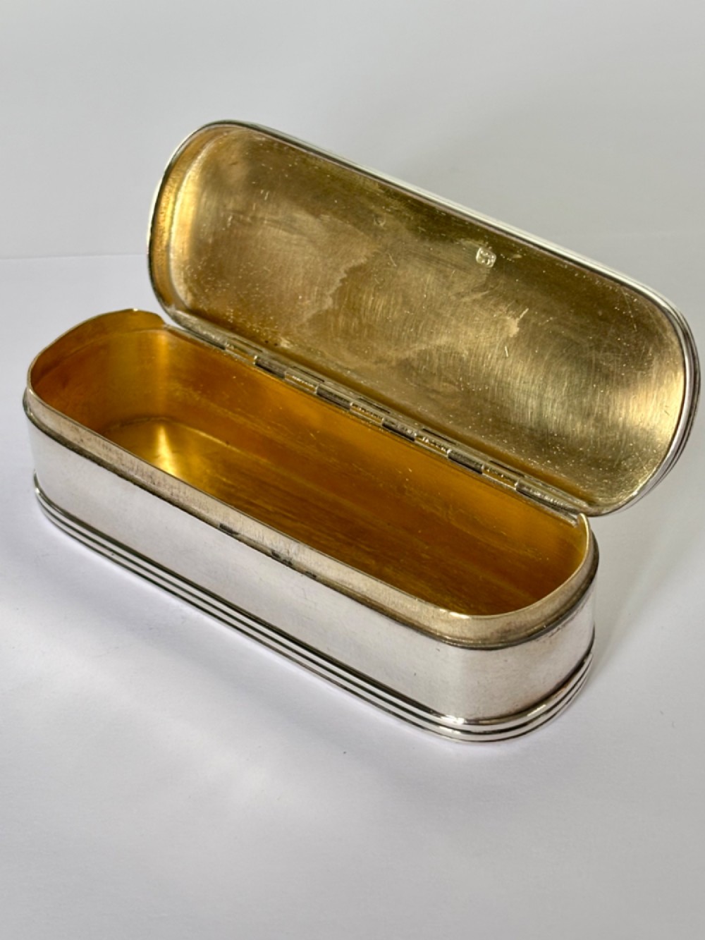 An elongated Georgian sterling silver snuff box with rounded ends, engraved on the lid with the Isle of Man triskelion crest. View IV