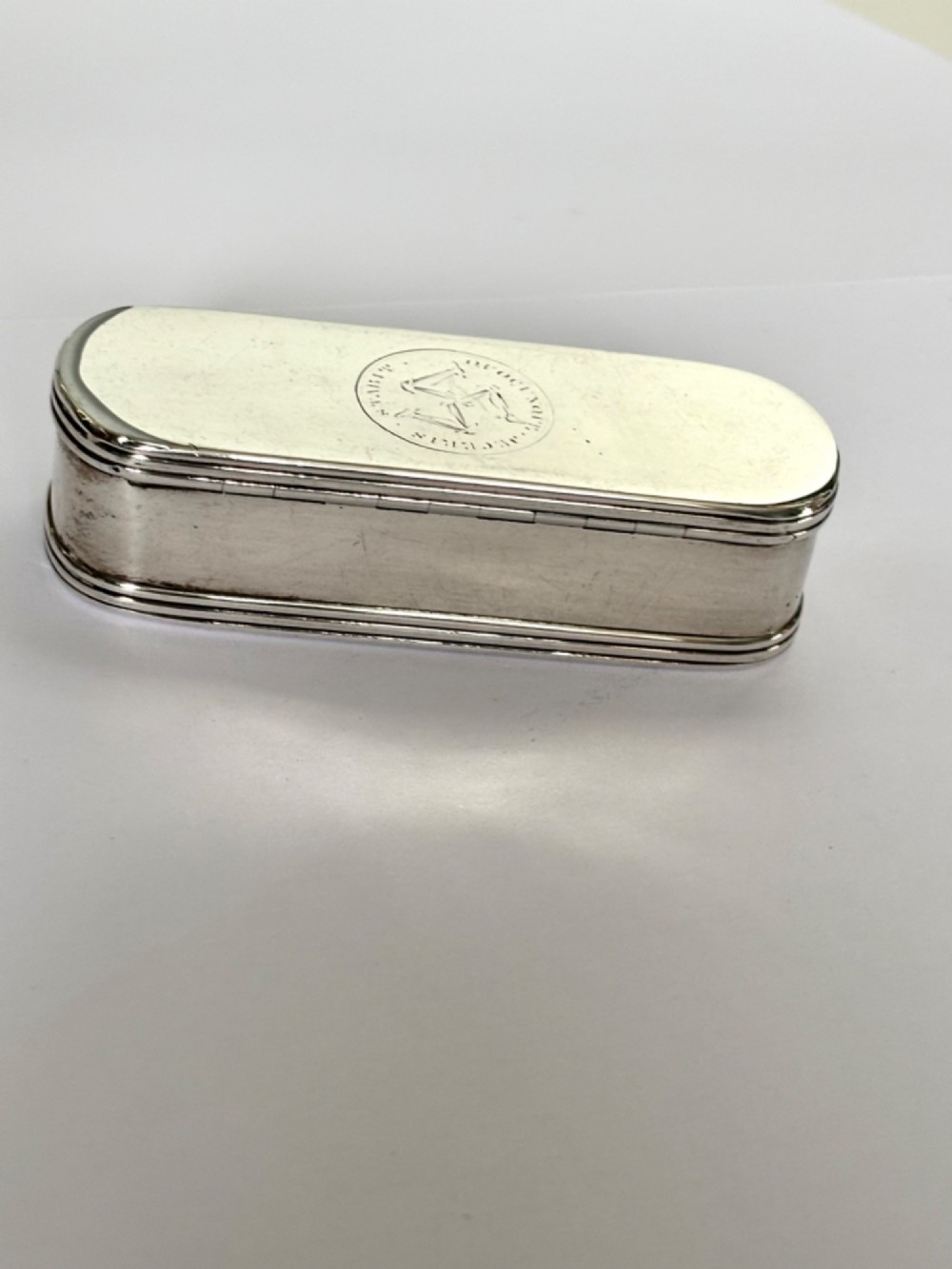 An elongated Georgian sterling silver snuff box with rounded ends, engraved on the lid with the Isle of Man triskelion crest. View XI