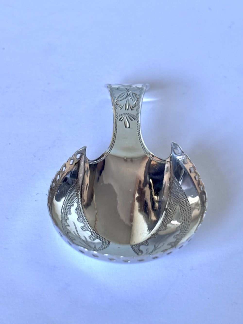 A Georgian sterling silver caddy spoon featuring a pastern hoof shaped bowl with bright-cut engraved decoration and a short handle. View III
