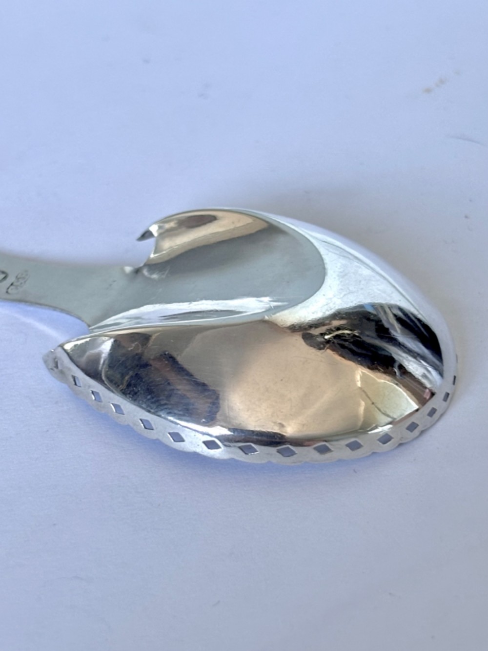 A Georgian sterling silver caddy spoon featuring a pastern hoof shaped bowl with bright-cut engraved decoration and a short handle. View V