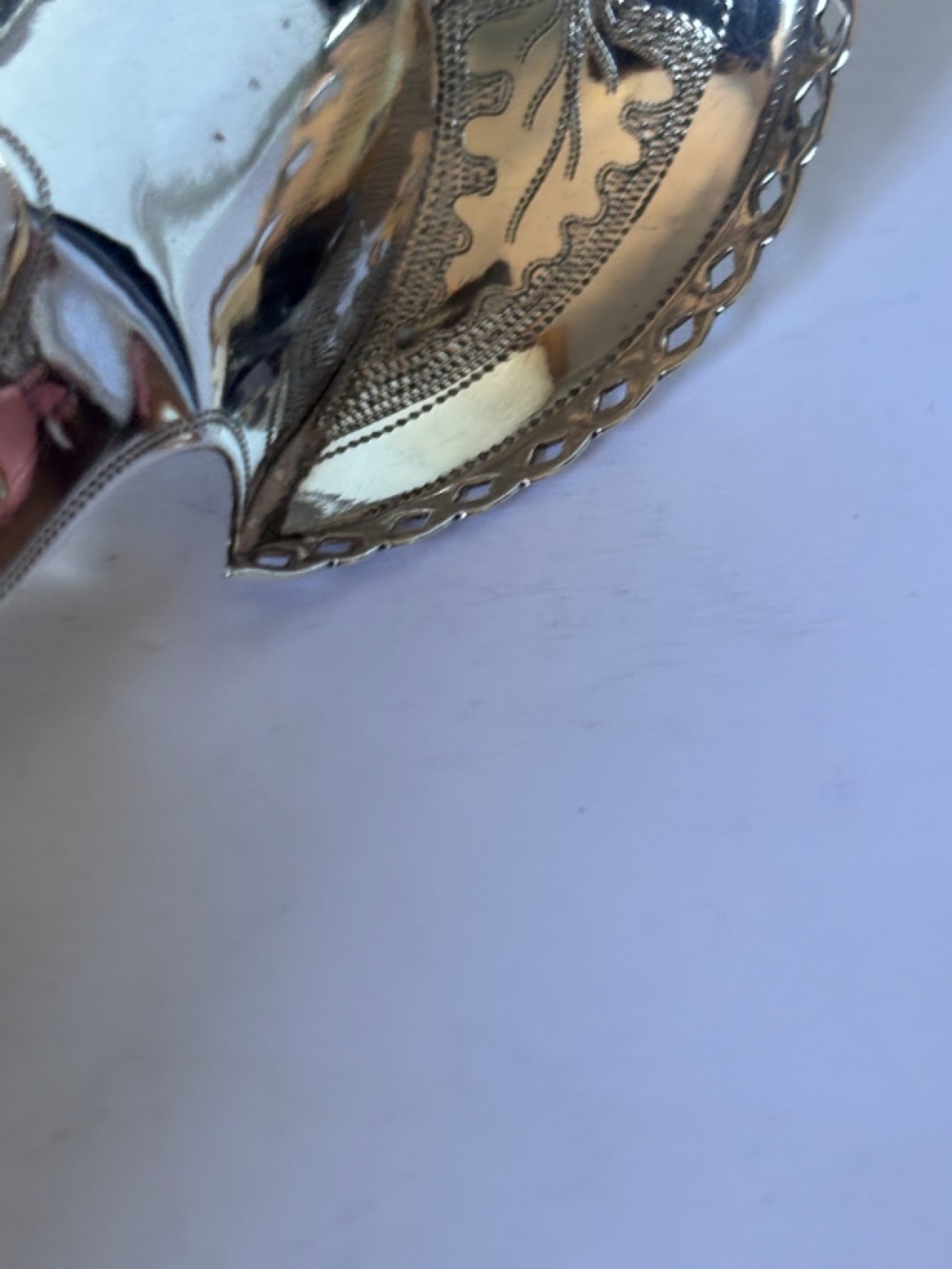 A Georgian sterling silver caddy spoon featuring a pastern hoof shaped bowl with bright-cut engraved decoration and a short handle. View VI