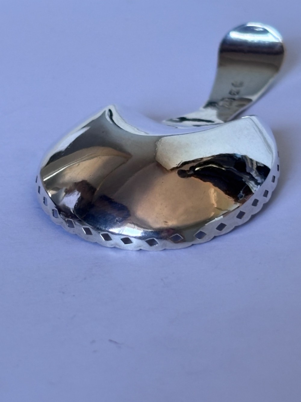 A Georgian sterling silver caddy spoon featuring a pastern hoof shaped bowl with bright-cut engraved decoration and a short handle. View VII