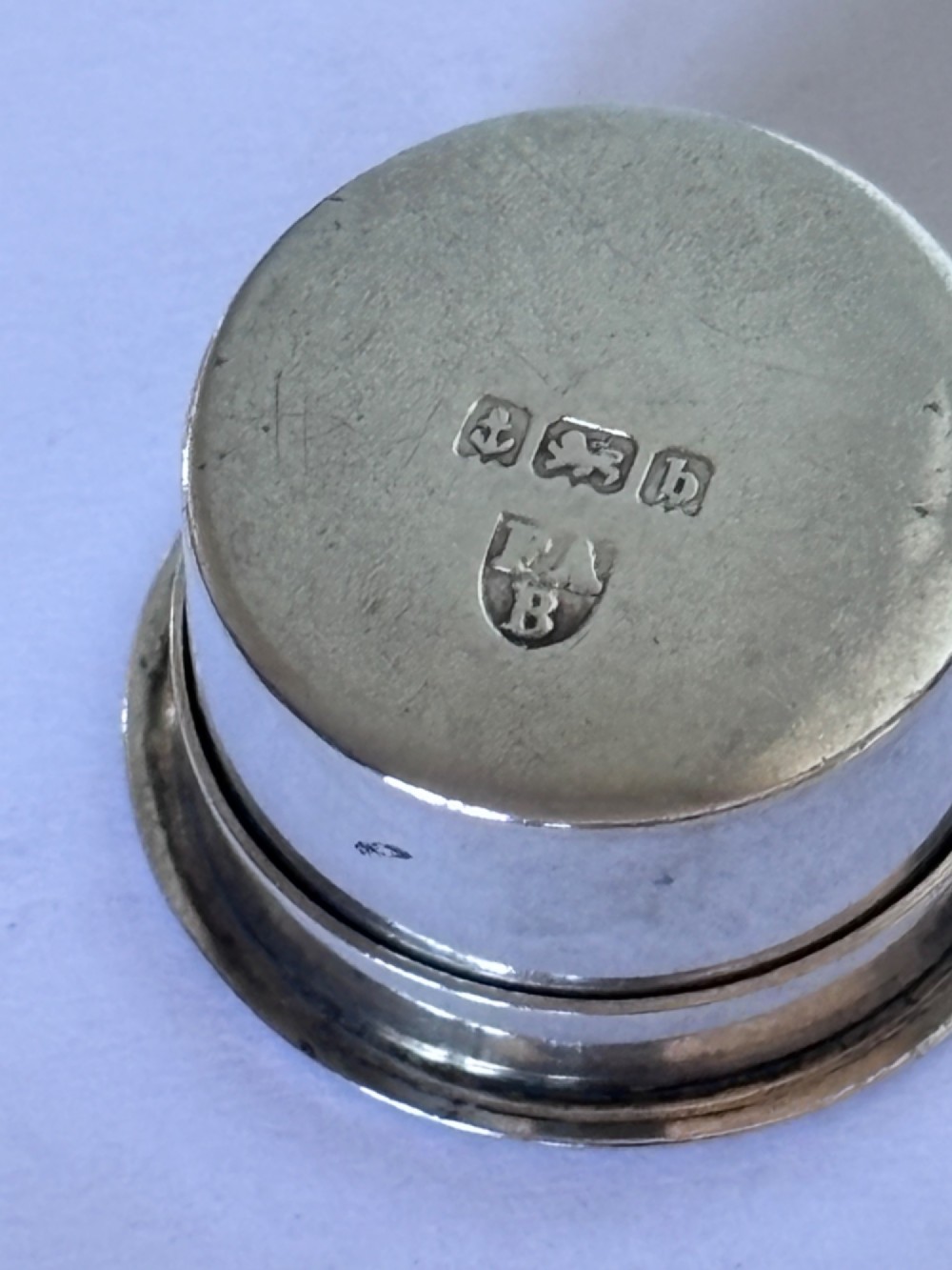 A circular sterling silver pyx box featuring an engraved monogram set against a textured hatch pattern on the lid. View IV