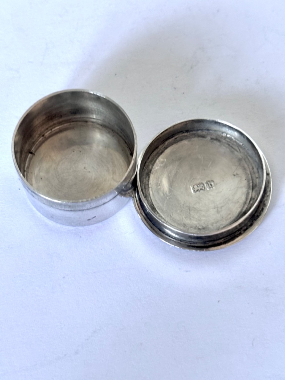 A circular sterling silver pyx box featuring an engraved monogram set against a textured hatch pattern on the lid. View VI