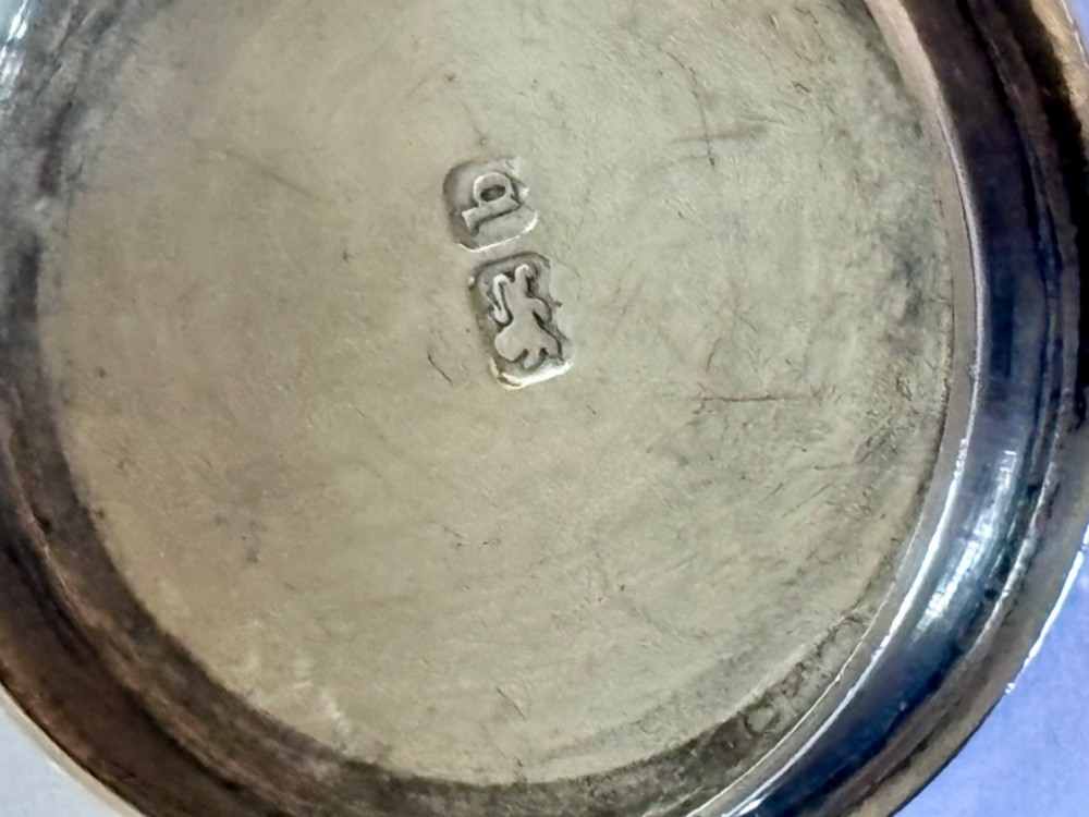 A circular sterling silver pyx box featuring an engraved monogram set against a textured hatch pattern on the lid. View VII