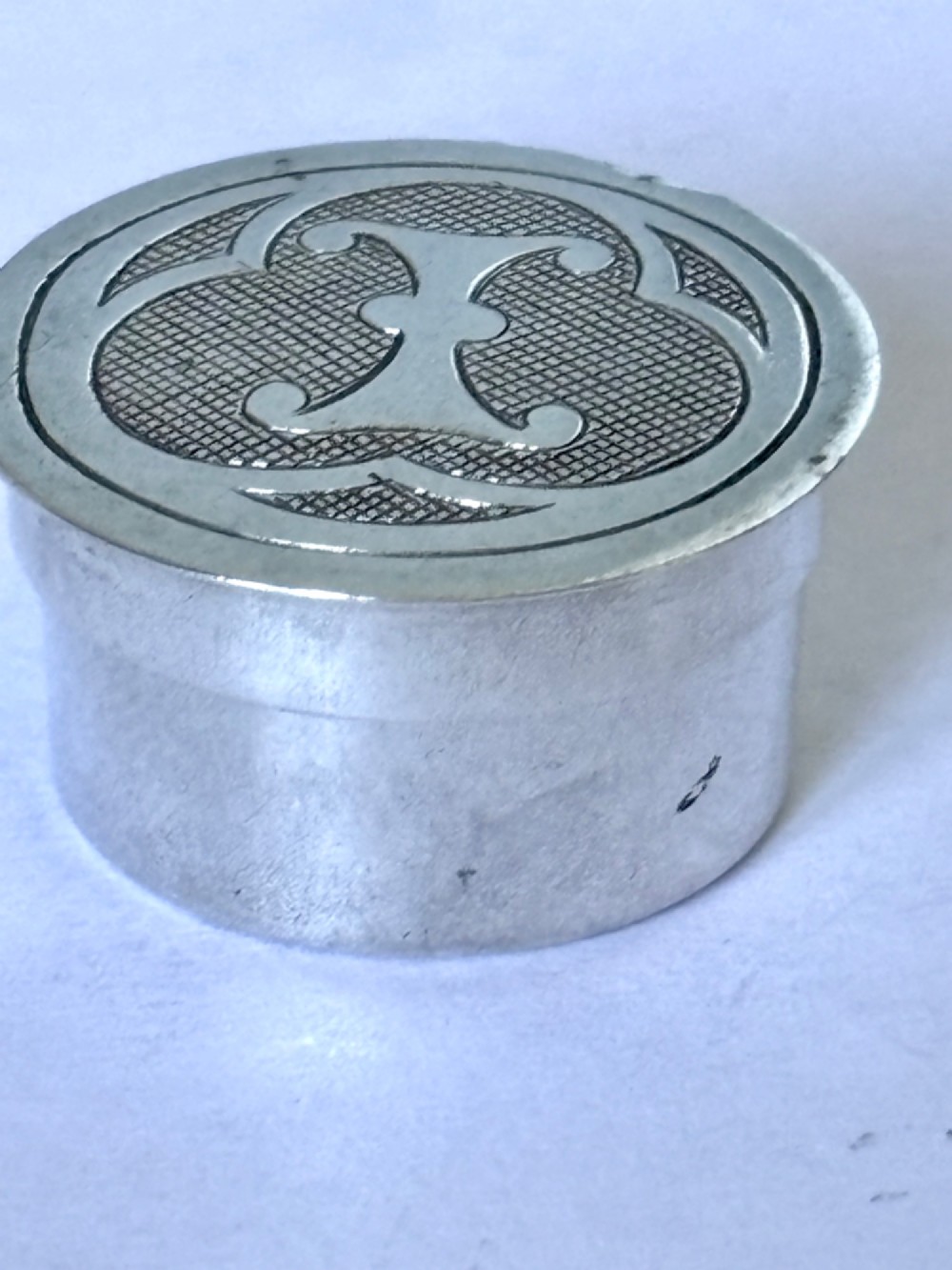 A circular sterling silver pyx box featuring an engraved monogram set against a textured hatch pattern on the lid. View VIII