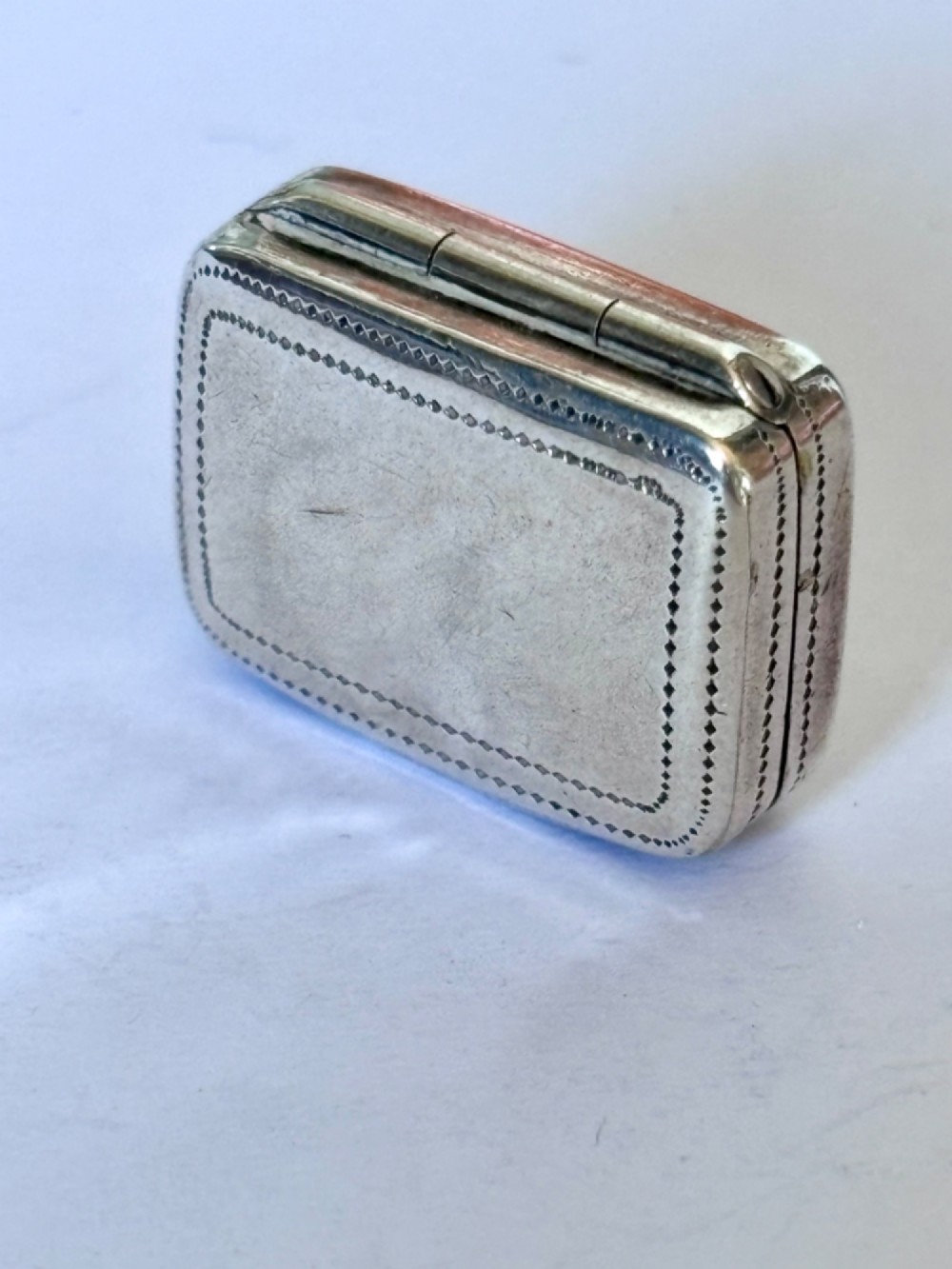 A small rectangular Georgian silver vinaigrette box with hand-engraved wrigglework patterns and a plain central oval cartouche. View II
