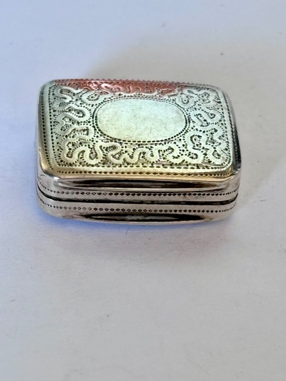 A small rectangular Georgian silver vinaigrette box with hand-engraved wrigglework patterns and a plain central oval cartouche. View III