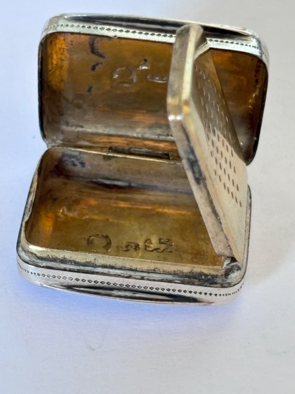 A small rectangular Georgian silver vinaigrette box with hand-engraved wrigglework patterns and a plain central oval cartouche. View V