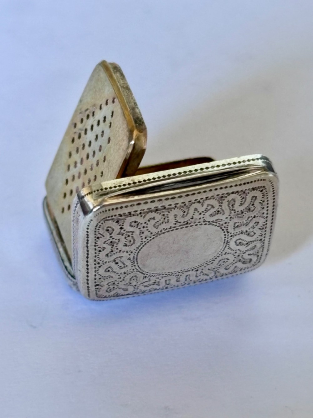 A small rectangular Georgian silver vinaigrette box with hand-engraved wrigglework patterns and a plain central oval cartouche. View IX
