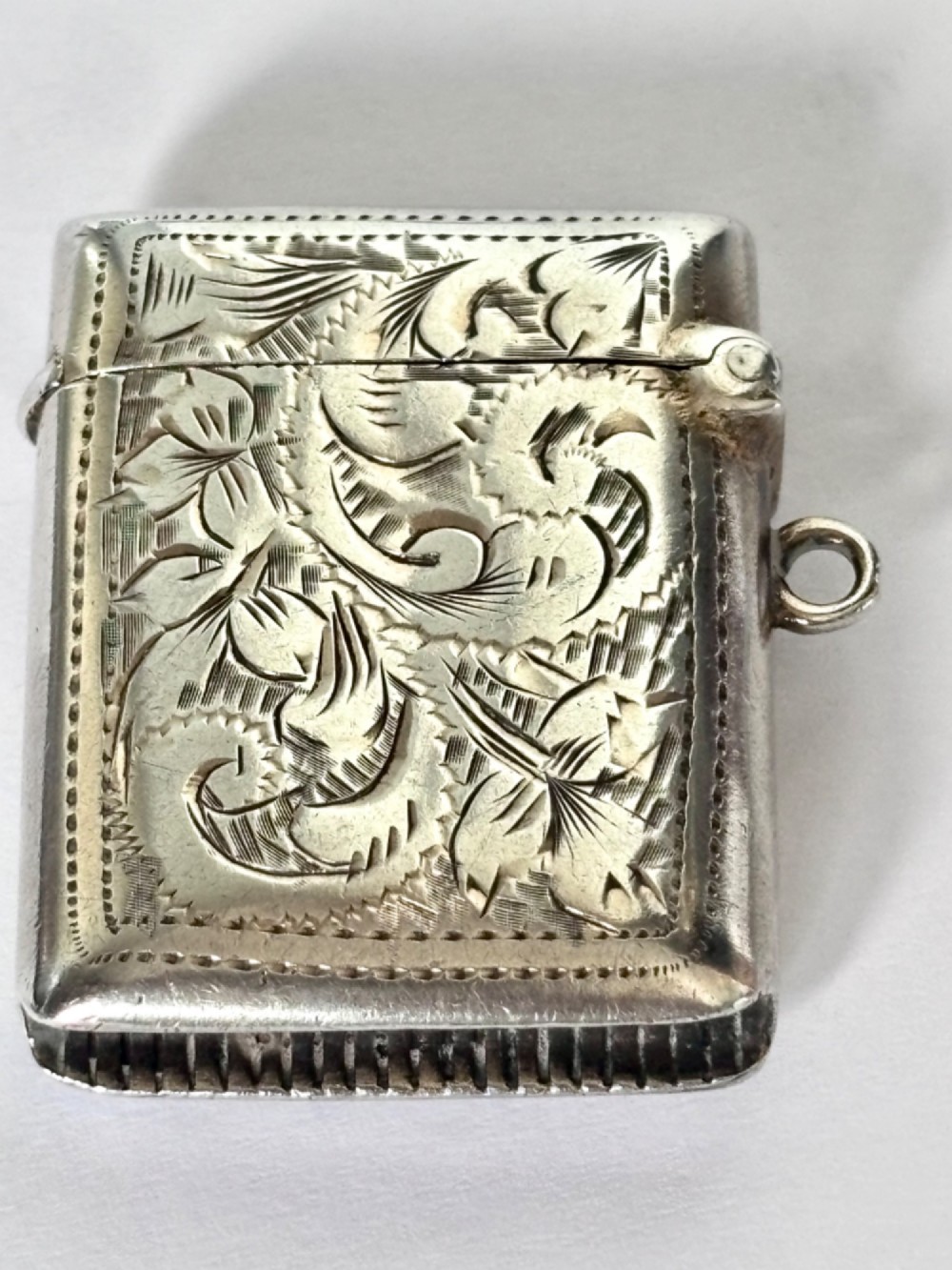 A rectangular Victorian sterling silver vesta case featuring hand-engraved scrollwork, a vacant central cartouche, and a side attachment ring. View IV