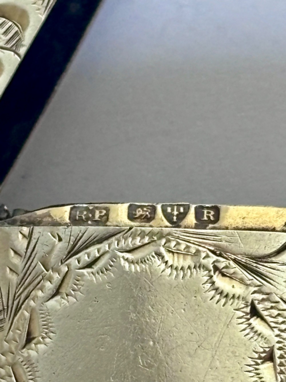 A rectangular Victorian sterling silver vesta case featuring hand-engraved scrollwork, a vacant central cartouche, and a side attachment ring. View VI