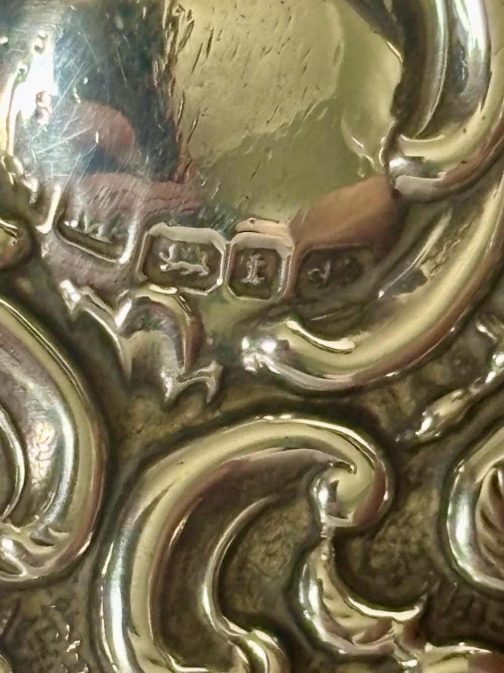 A Victorian rectangular sterling silver snuff box with heavily embossed floral and scroll decoration surrounding a plain central cartouche. View V