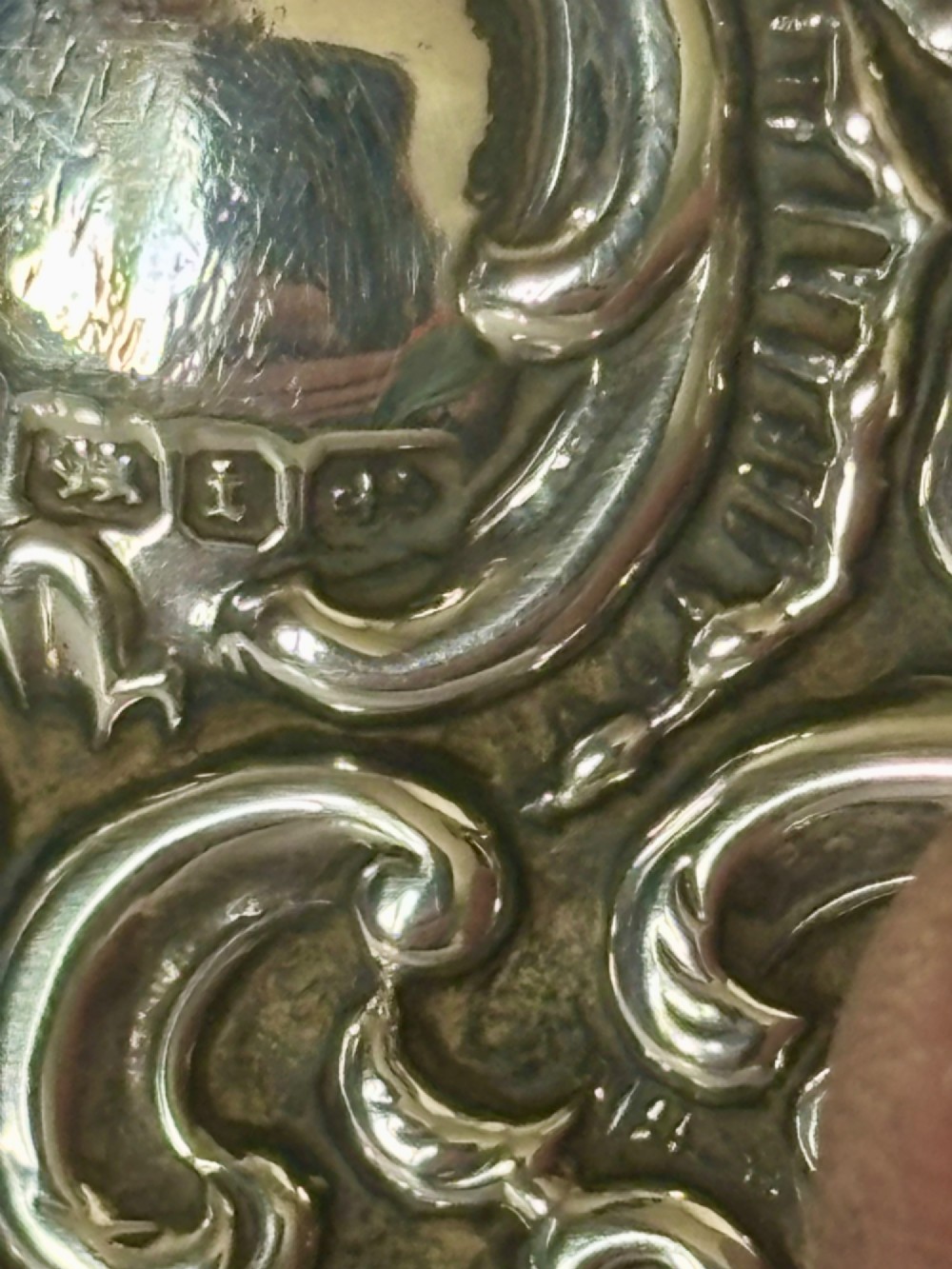 A Victorian rectangular sterling silver snuff box with heavily embossed floral and scroll decoration surrounding a plain central cartouche. View VI