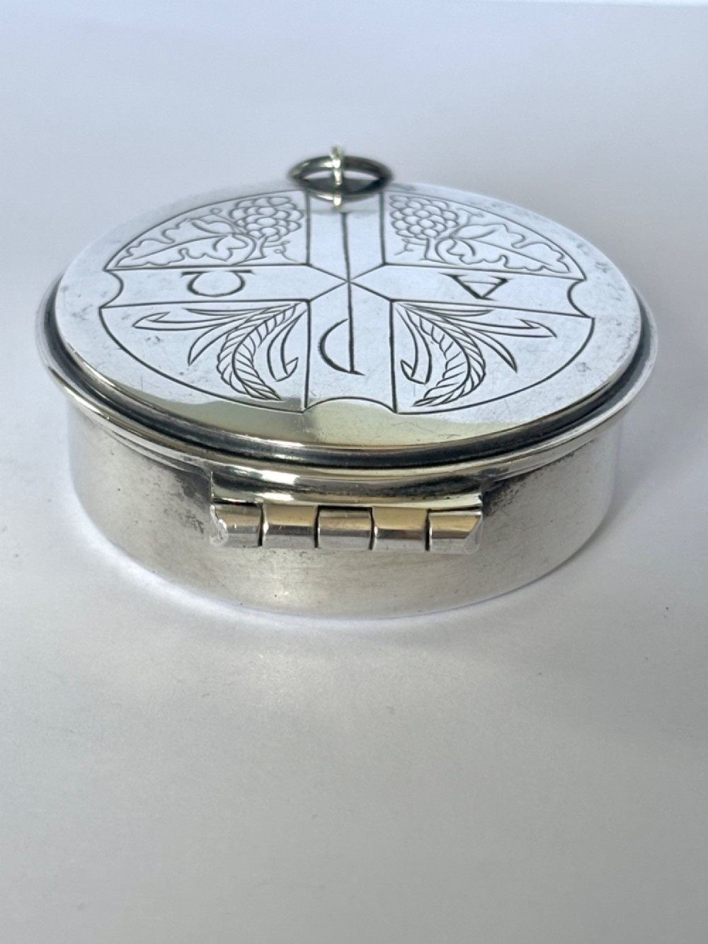 A small round sterling silver pyx box shown open, featuring a silver exterior and a gold-gilt interior stamped with hallmarks. View III