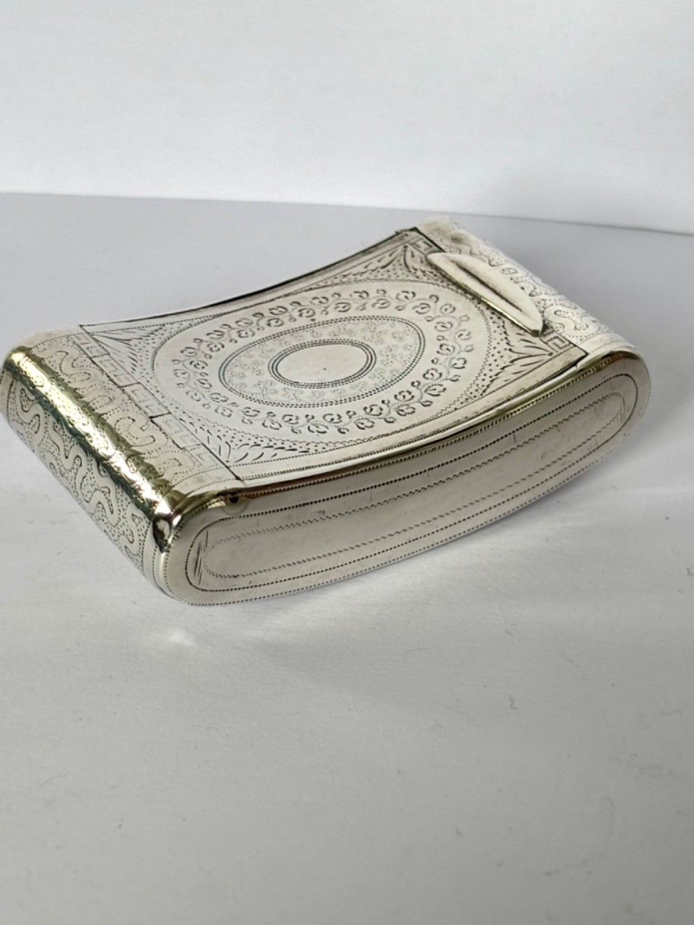 A curved antique sterling silver pocket snuff box featuring elaborate hand engraving and a flush hinge. View V