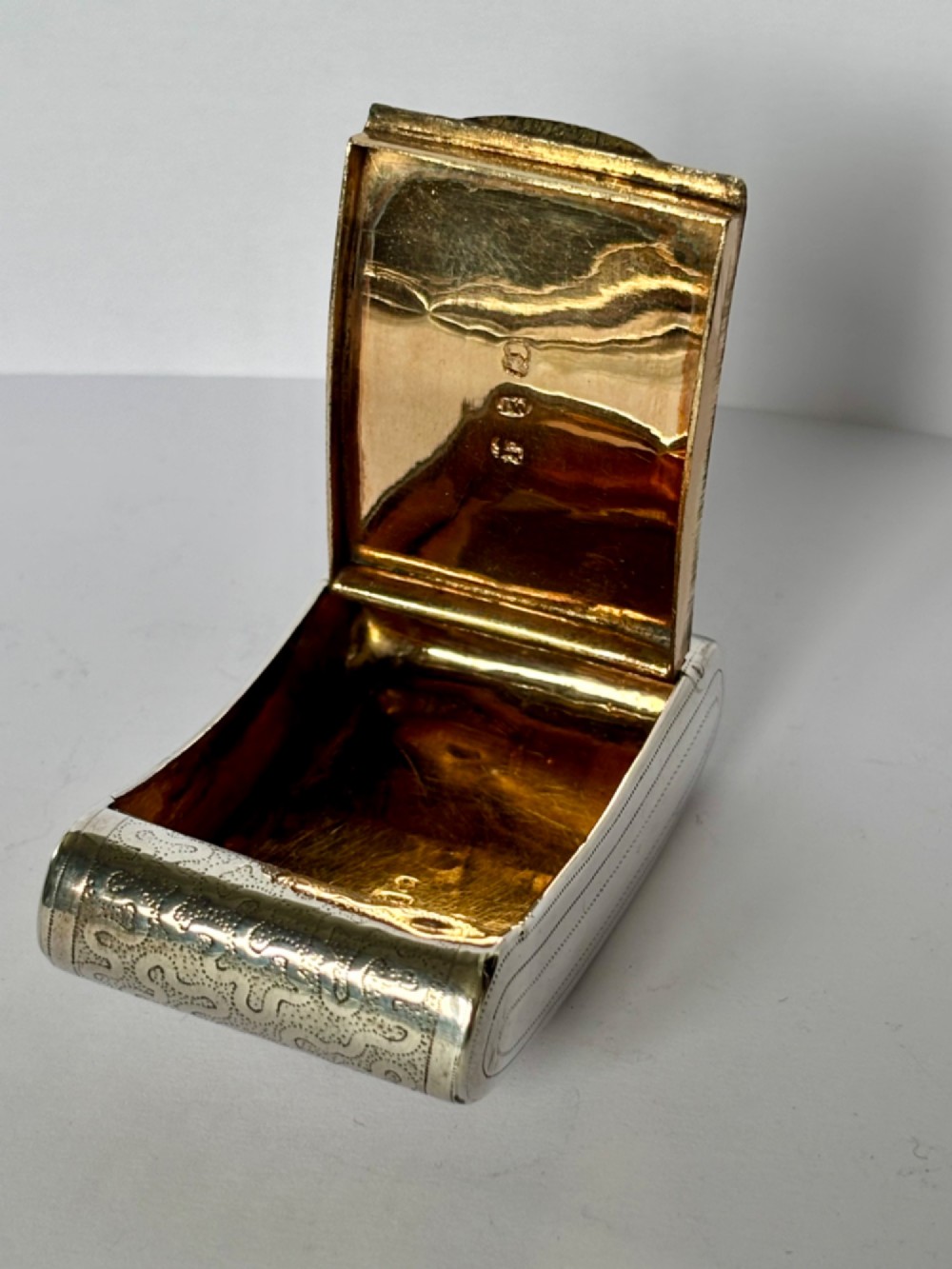 A curved antique sterling silver pocket snuff box featuring elaborate hand engraving and a flush hinge. View VI