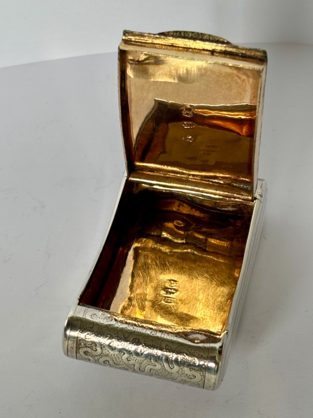 A curved antique sterling silver pocket snuff box featuring elaborate hand engraving and a flush hinge. View VII