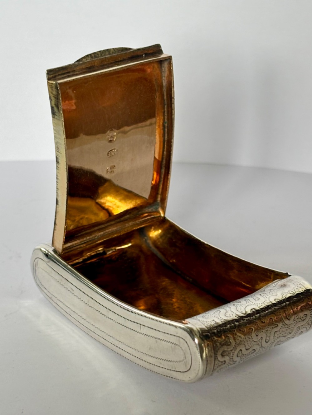 A curved antique sterling silver pocket snuff box featuring elaborate hand engraving and a flush hinge. View VIII