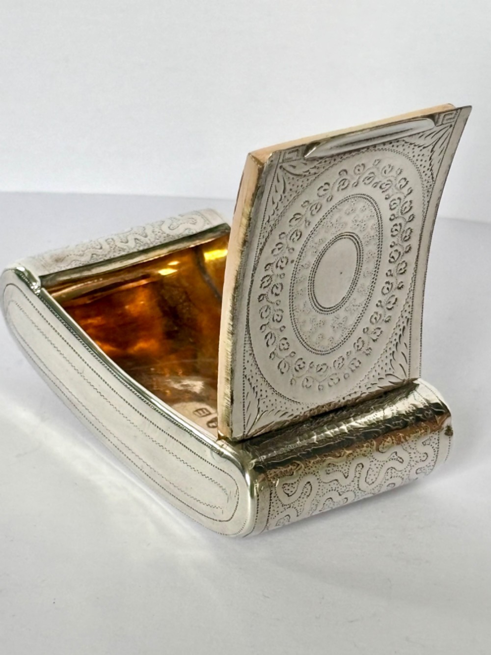 A curved antique sterling silver pocket snuff box featuring elaborate hand engraving and a flush hinge. View IX