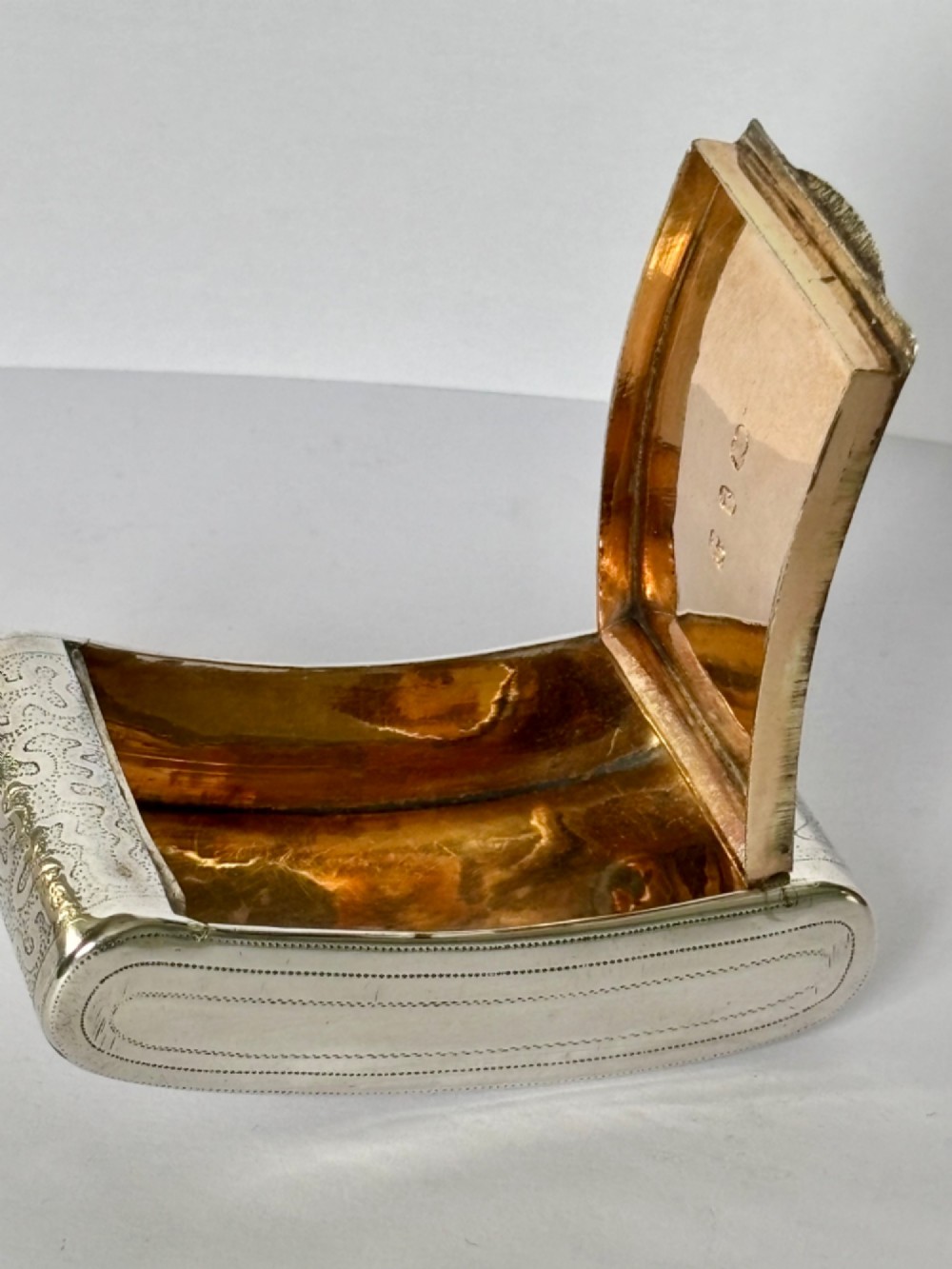 A curved antique sterling silver pocket snuff box featuring elaborate hand engraving and a flush hinge. View X