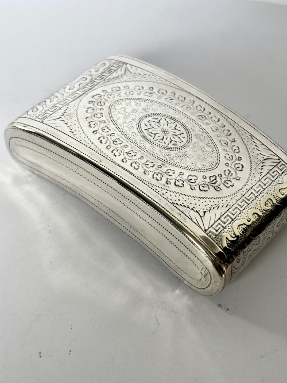 A curved antique sterling silver pocket snuff box featuring elaborate hand engraving and a flush hinge. View XII