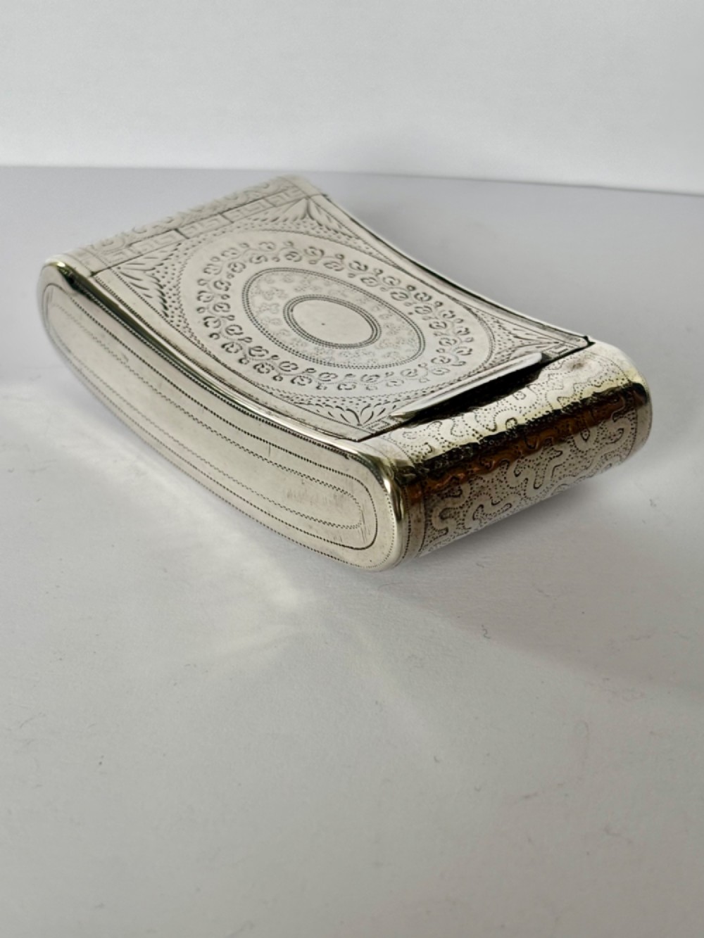 A curved antique sterling silver pocket snuff box featuring elaborate hand engraving and a flush hinge. View XV