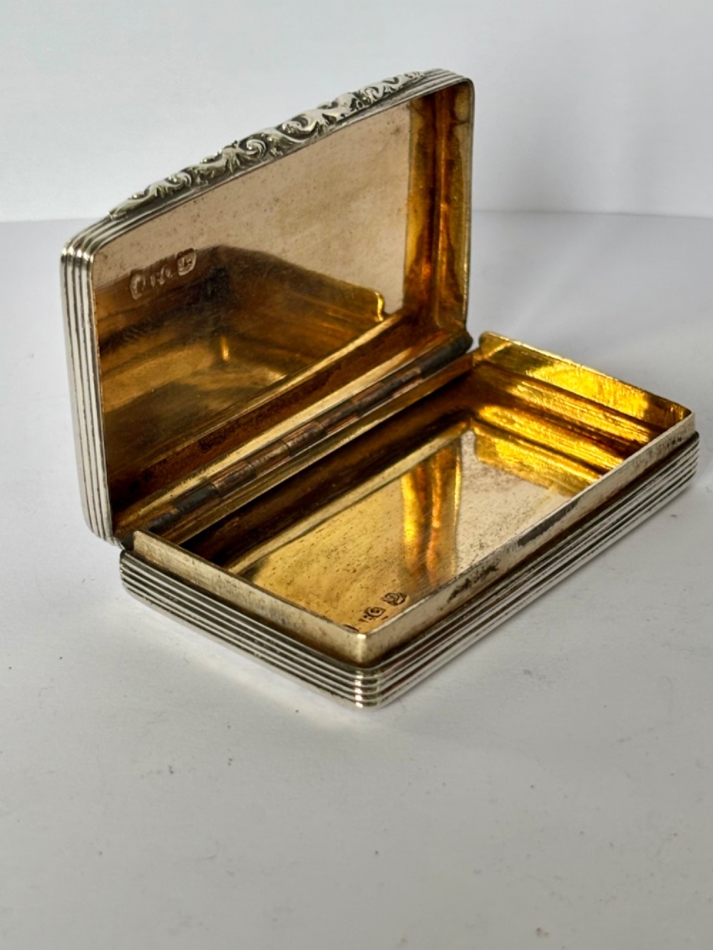 A rectangular Georgian sterling silver snuff box displaying geometric engine-turned patterns, a blank central cartouche, and reeded side edges. View VIII