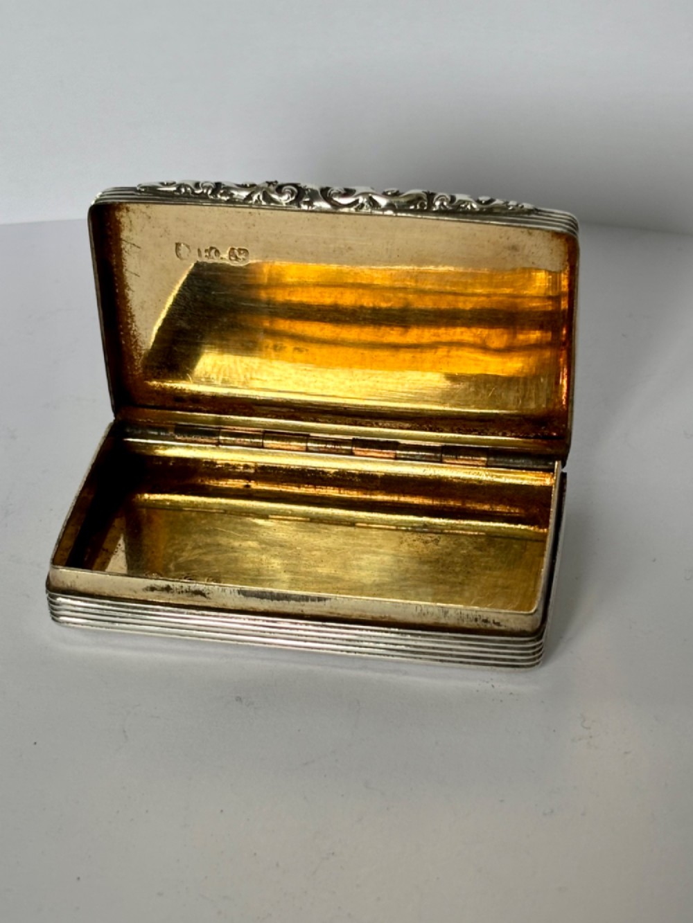 A rectangular Georgian sterling silver snuff box displaying geometric engine-turned patterns, a blank central cartouche, and reeded side edges. View XI