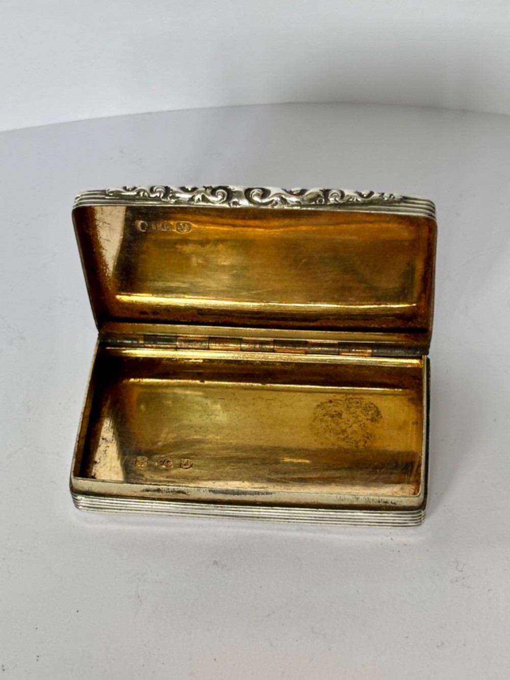 A rectangular Georgian sterling silver snuff box displaying geometric engine-turned patterns, a blank central cartouche, and reeded side edges. View XII