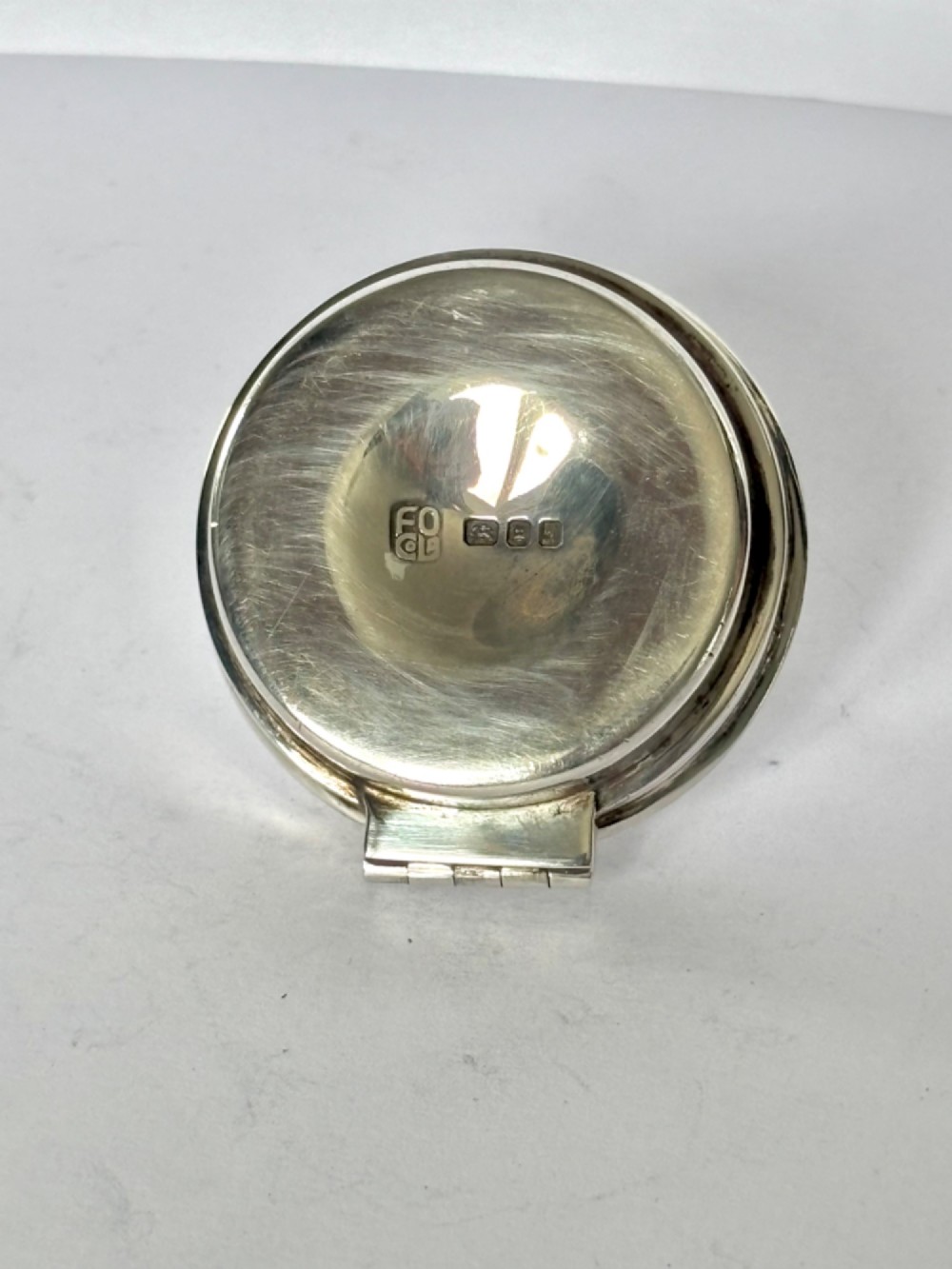 A circular sterling silver pyx box with a polished finish, featuring a lid topped with a cross and orb finial. View VI