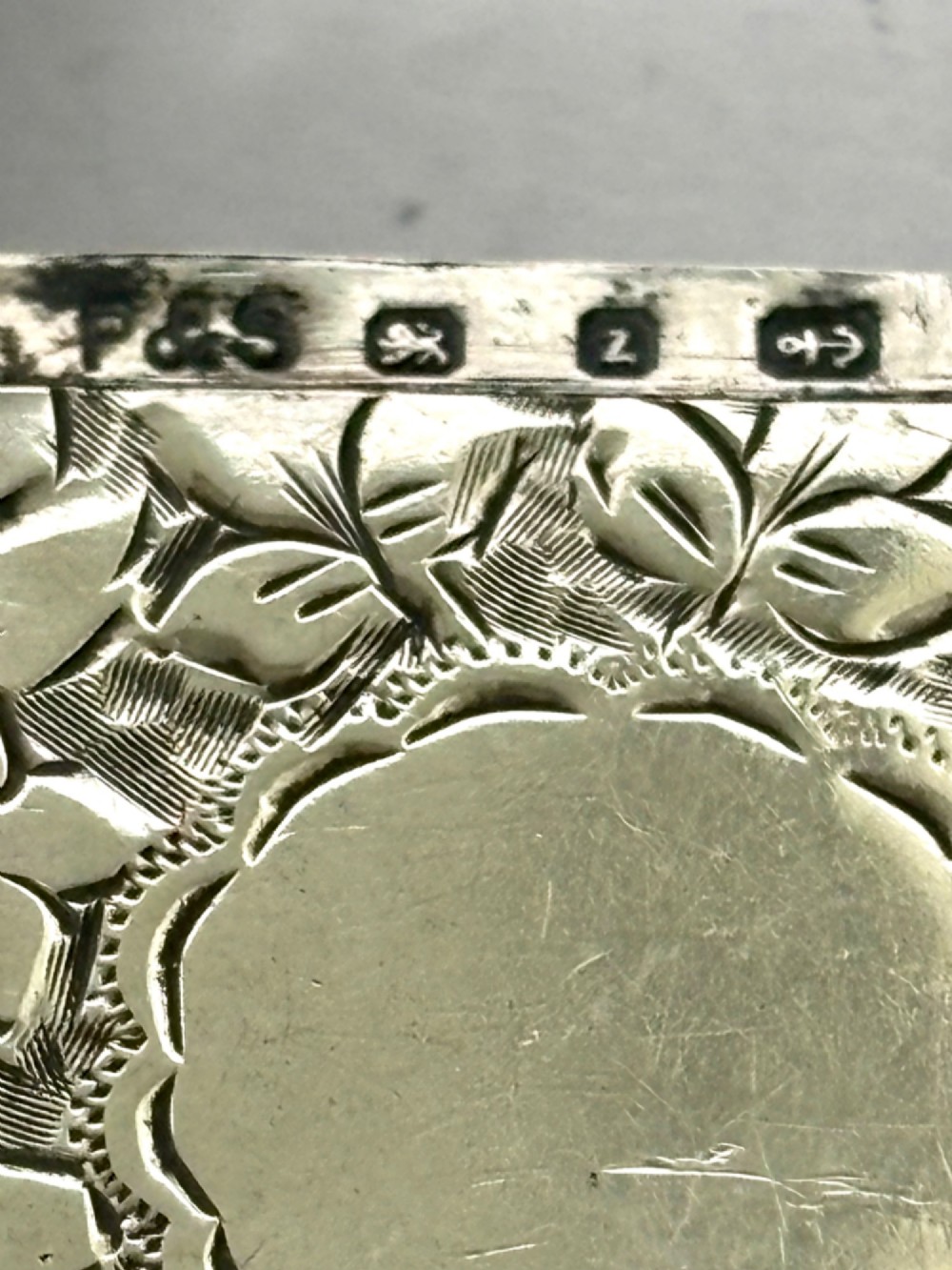 A Victorian sterling silver vesta case featuring hand-engraved floral leaf motifs, gadrooned corners, a vacant central cartouche, and a side suspension ring. View III