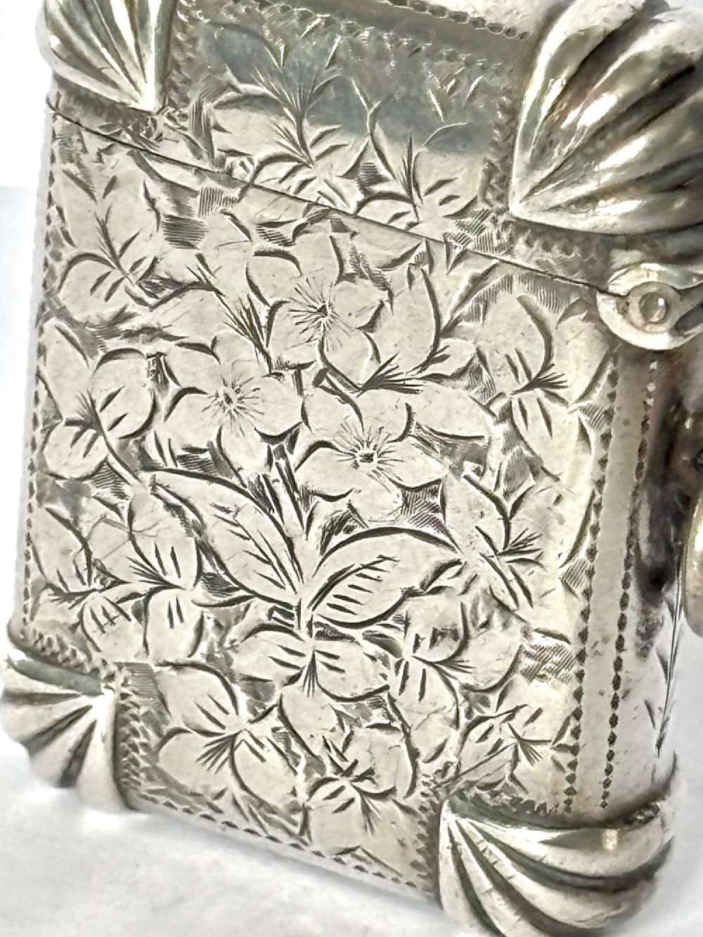 A Victorian sterling silver vesta case featuring hand-engraved floral leaf motifs, gadrooned corners, a vacant central cartouche, and a side suspension ring. View V