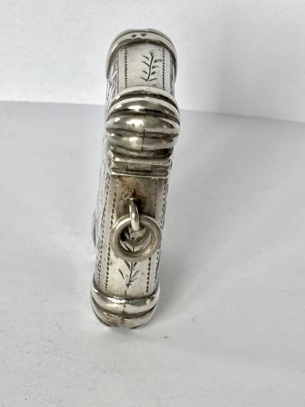 A Victorian sterling silver vesta case featuring hand-engraved floral leaf motifs, gadrooned corners, a vacant central cartouche, and a side suspension ring. View VI